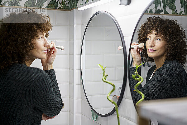 Woman applying make-up in bathroom at home