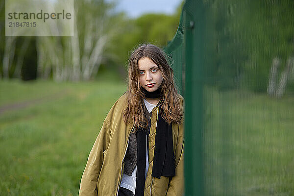 Beautiful young woman leaning on fence at back yard