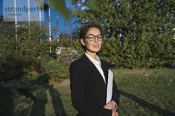 Smiling businesswoman with file folder in office park