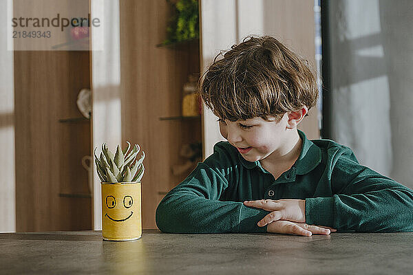 Boy looking at potted plant in home