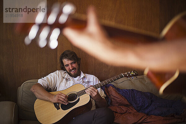 Two men play guitar together at home in Gold Hill  Colorado.