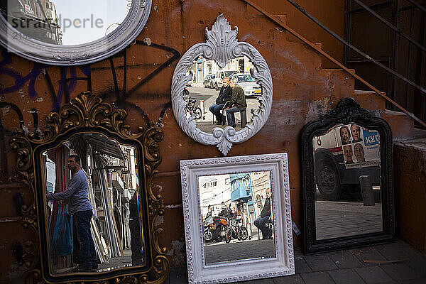 People are reflected in mirrors for sale on the street in Tel Aviv  Israel.