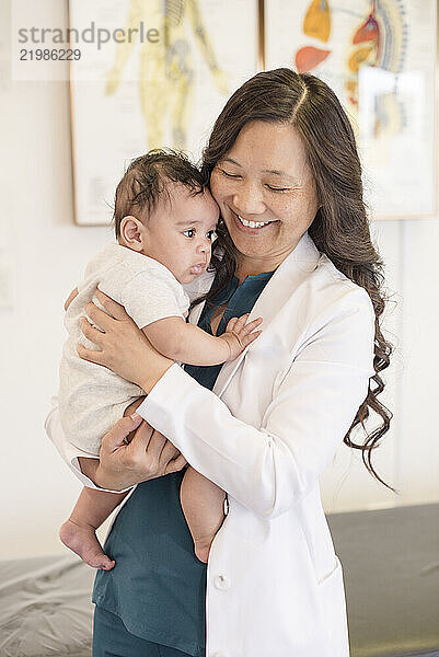 Doctor smiling while holding baby patient