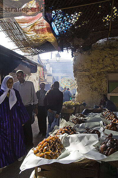 Shoppers gather around piles of large dried dates.