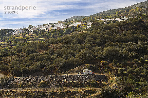 A traveler relaxes by her camper parked on a dirt road below the town of Pitres in Las Alpujarras  Andalusia  Spain.