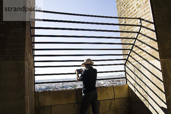 A tourist takes pictures from the top of La Giralda (cathedral tower) in Sevilla  Andalusia  Spain.