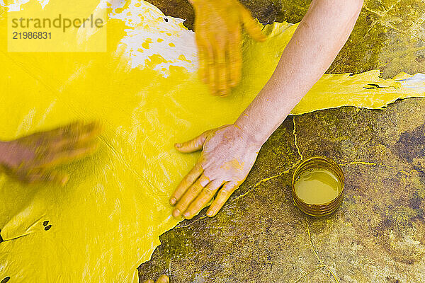 Workers rub yellow dye onto a sheep skin.