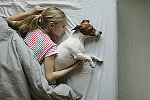 Blondes Mädchen im Bett liegend, ihr Hund schläft, Draufsicht